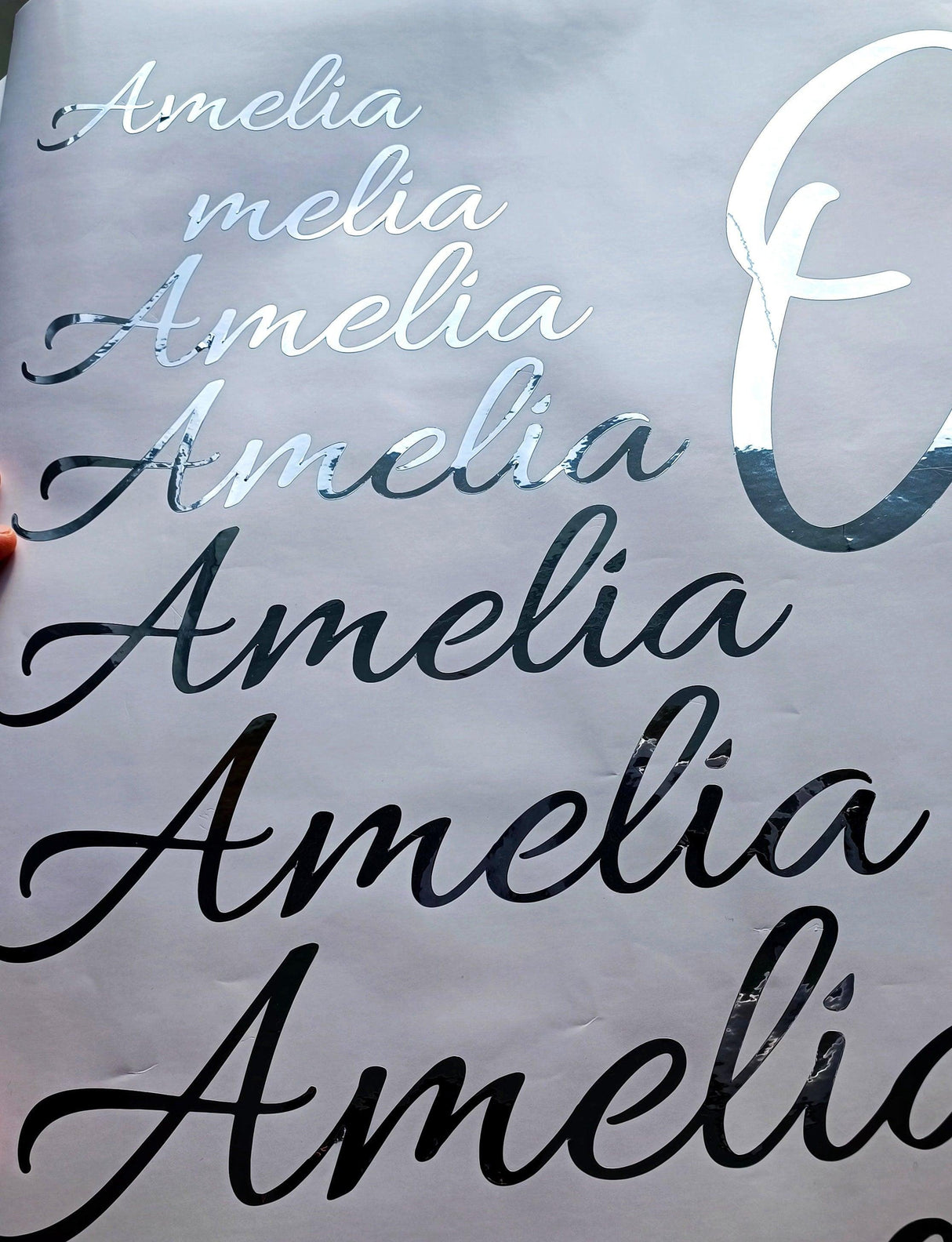 Personalized vinyl name stickers displaying various styles of the name 'Amelia' in silver chrome finish.