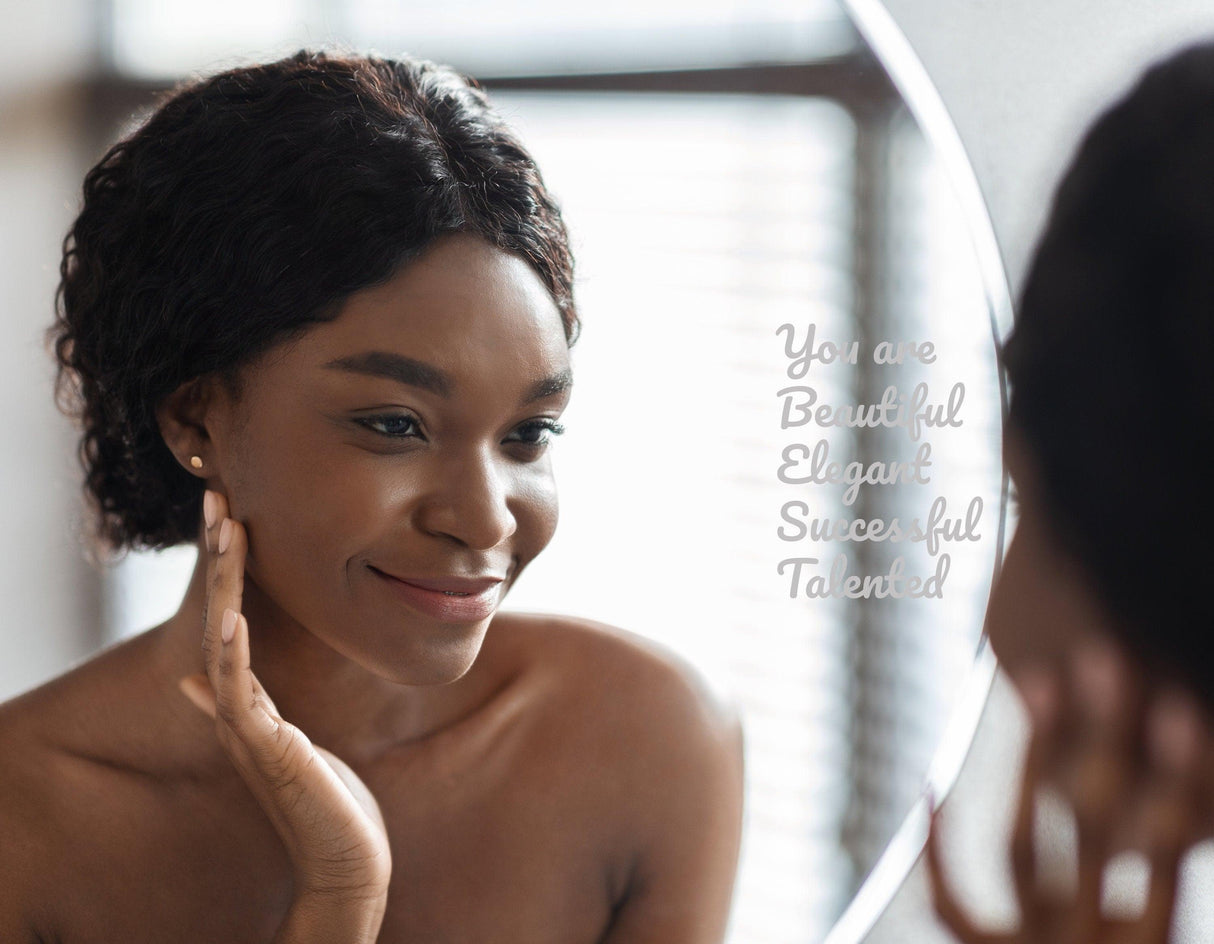 Smiling woman admiring herself in mirror with motivational affirmation decal: 'You are Beautiful, Elegant, Successful, Talented'.