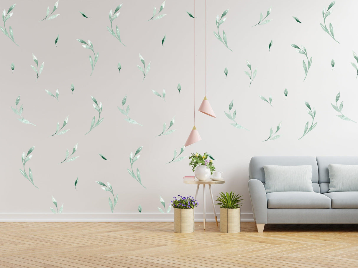 Leaf wall decor stickers in green leaf designs on a bright room wall with a cozy couch and plants.