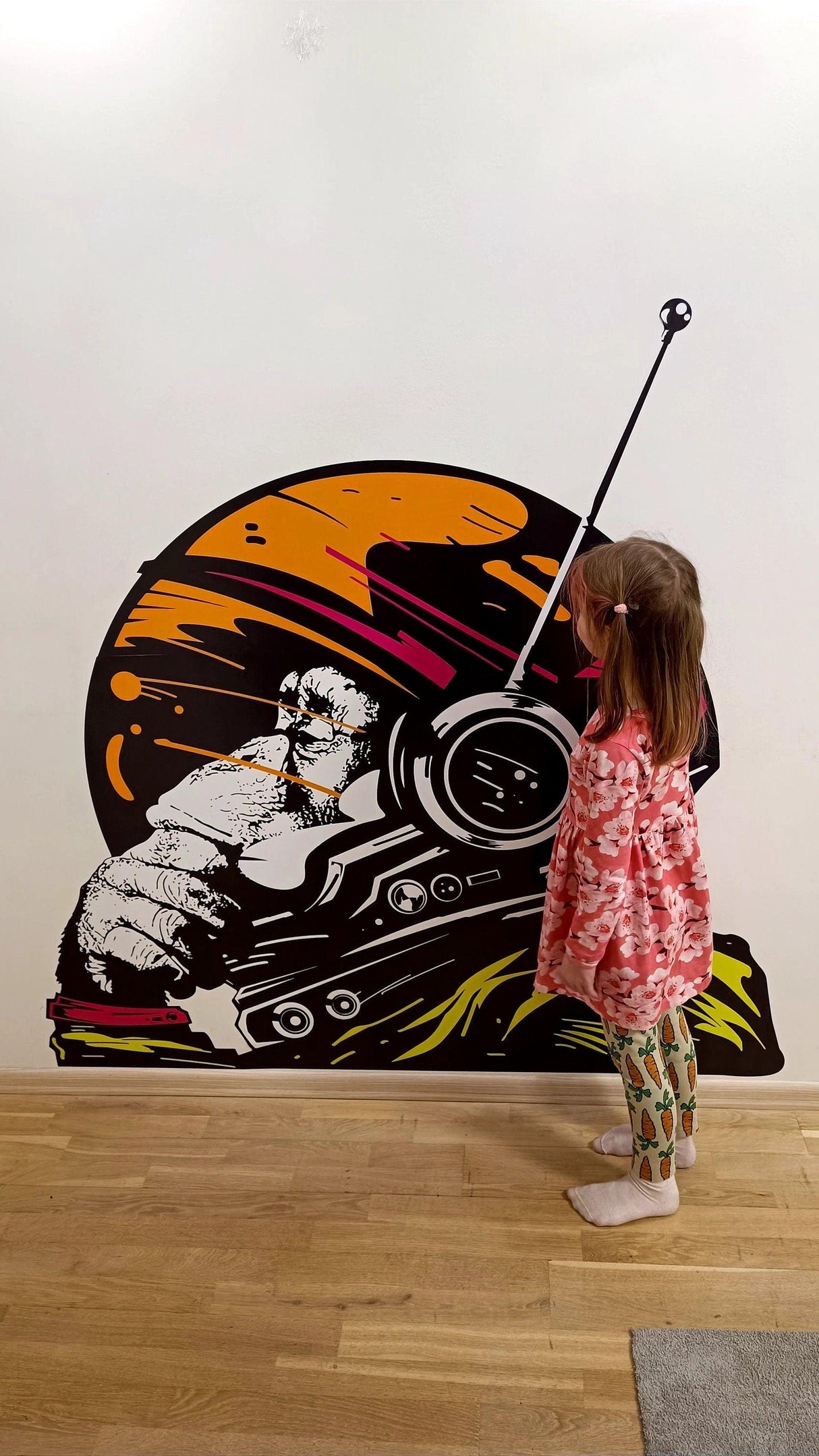 Child admiring a large astronaut space monkey wall sticker with vibrant colors and a playful design.