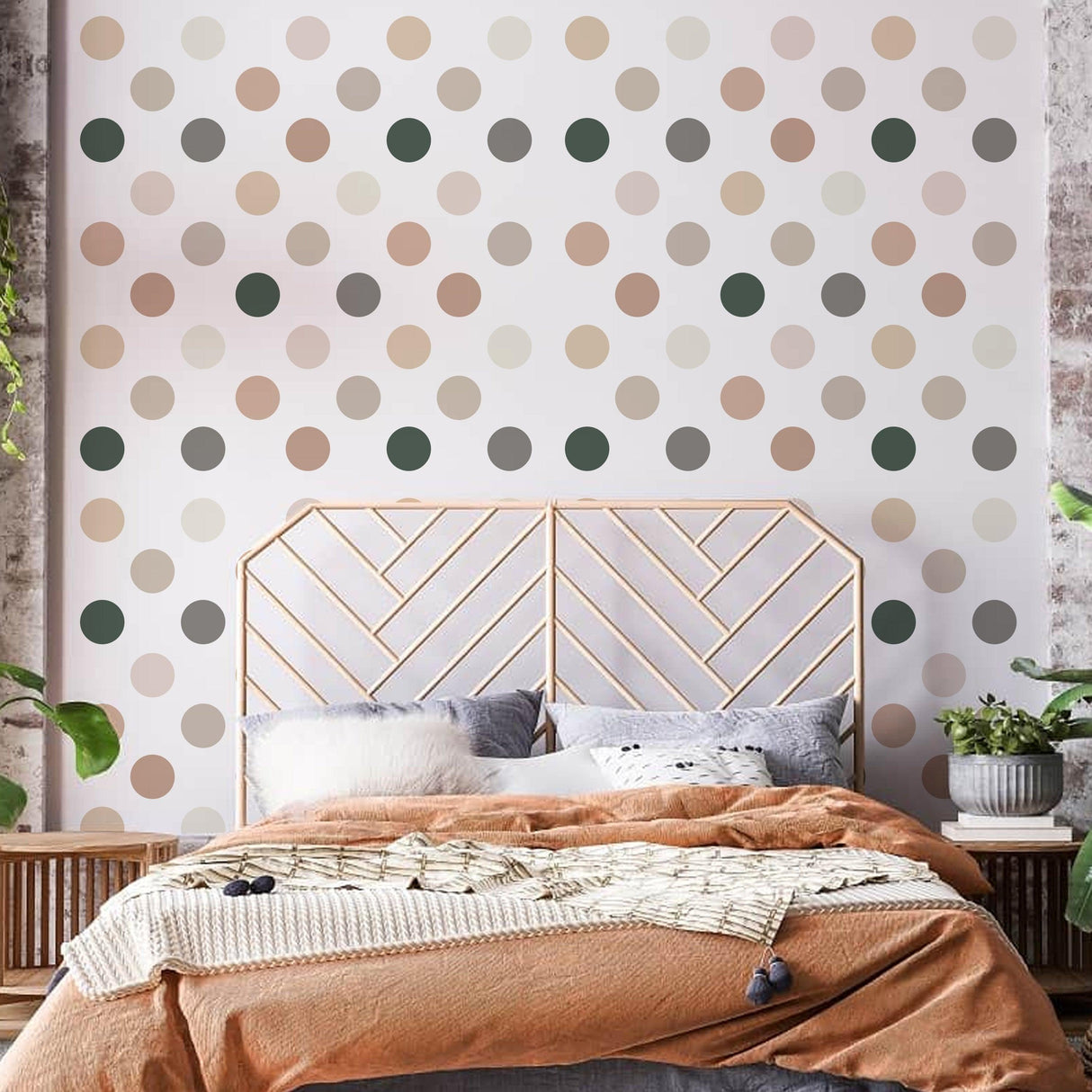 Neutral boho dots wall decals in pastel colors decorate a nursery with a cozy bed and greenery.