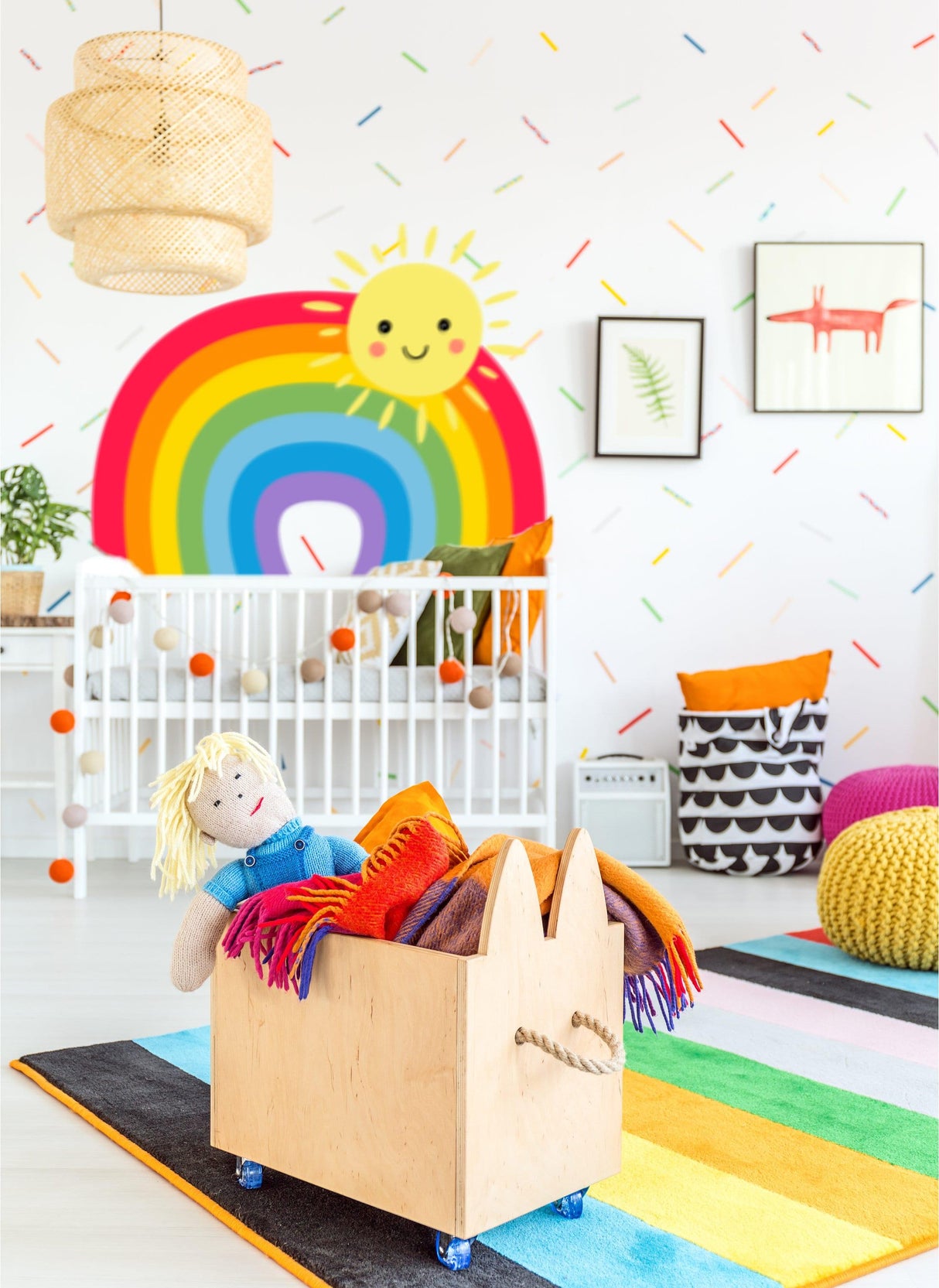 Colorful nursery featuring a rainbow wall sticker, wooden toy box, and plush toys creating a playful atmosphere.