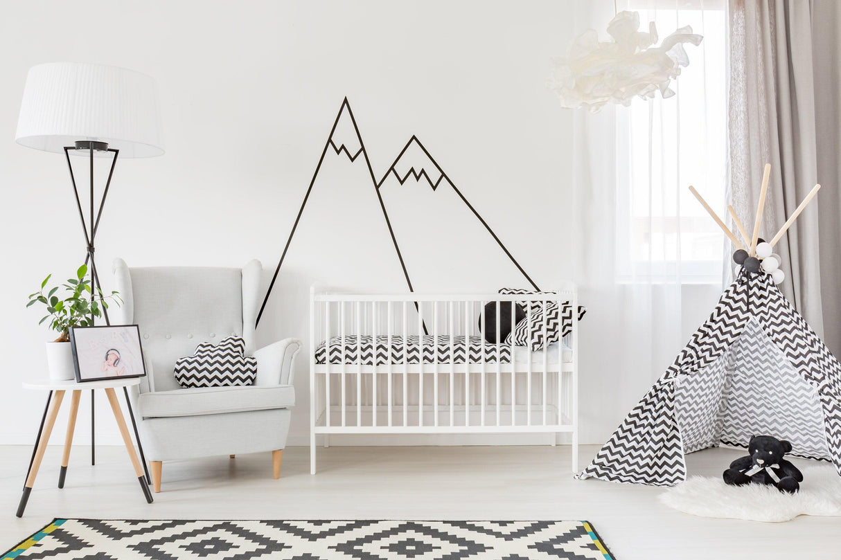 Nursery with black mountain wall decals, crib, armchair, and teepee for stylish home decor.