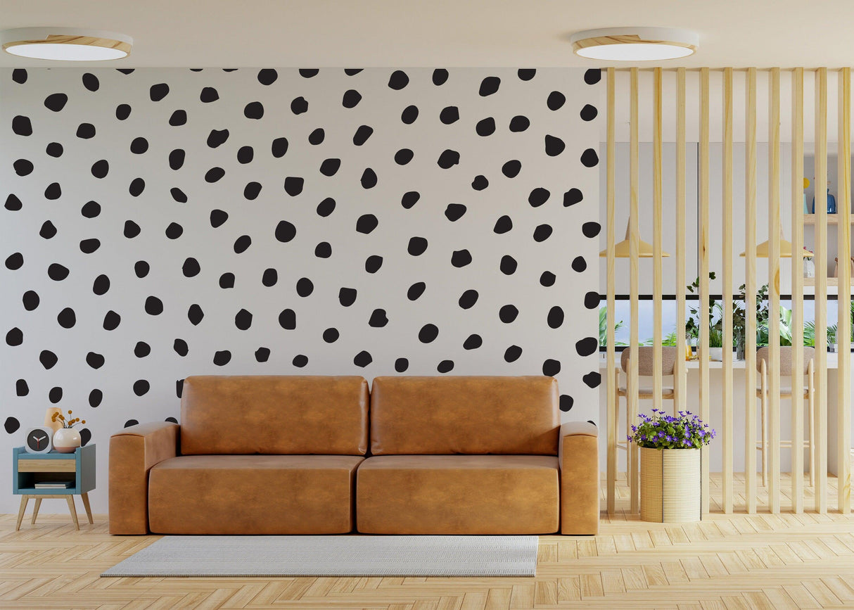 Living room featuring a modern wall with irregular black polka dots and a cozy brown couch.