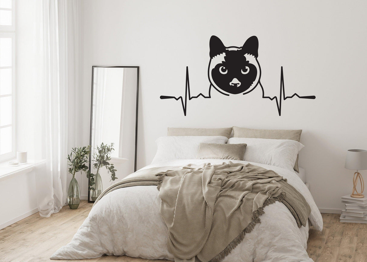 Siamese cat wall sticker with heartbeat design in a cozy bedroom setting.