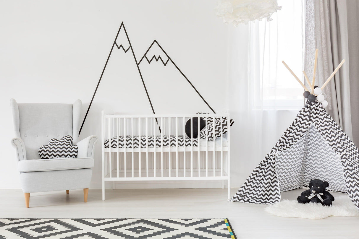 Black thin line mountain wall decals above a white crib in a stylish nursery with a black and white teepee.