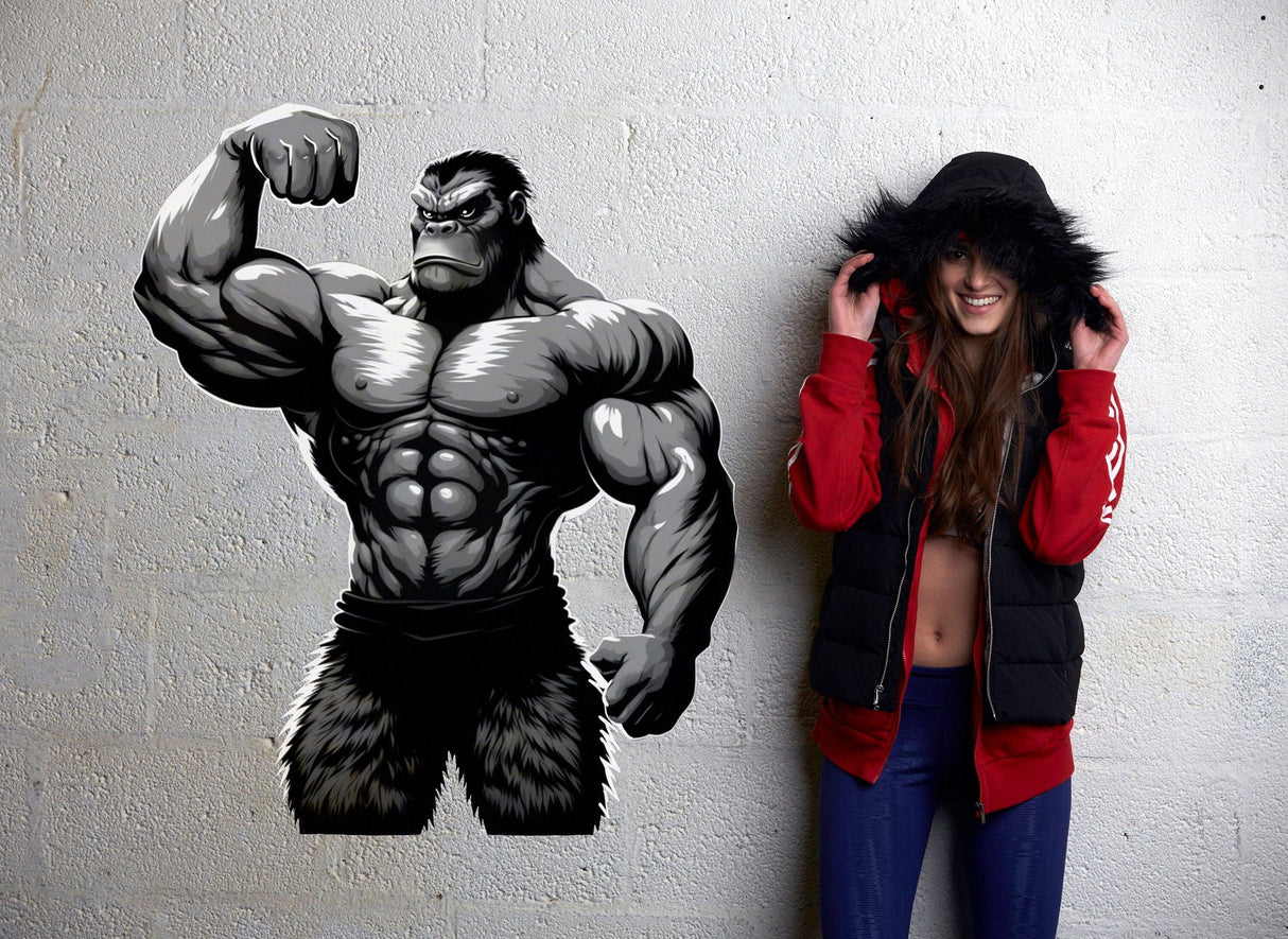 Muscled gorilla wall decal beside a fit woman in a hoodie, enhancing home gym decor and motivation.