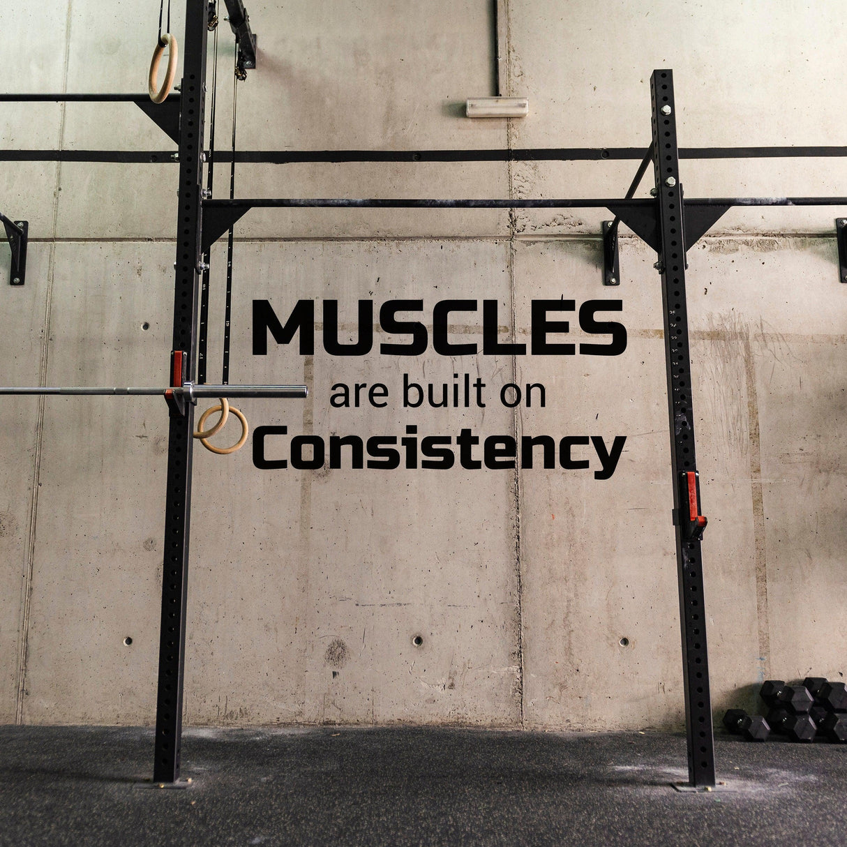 Gym wall decal displaying motivational quote: 'Muscles are built on Consistency' for fitness inspiration.