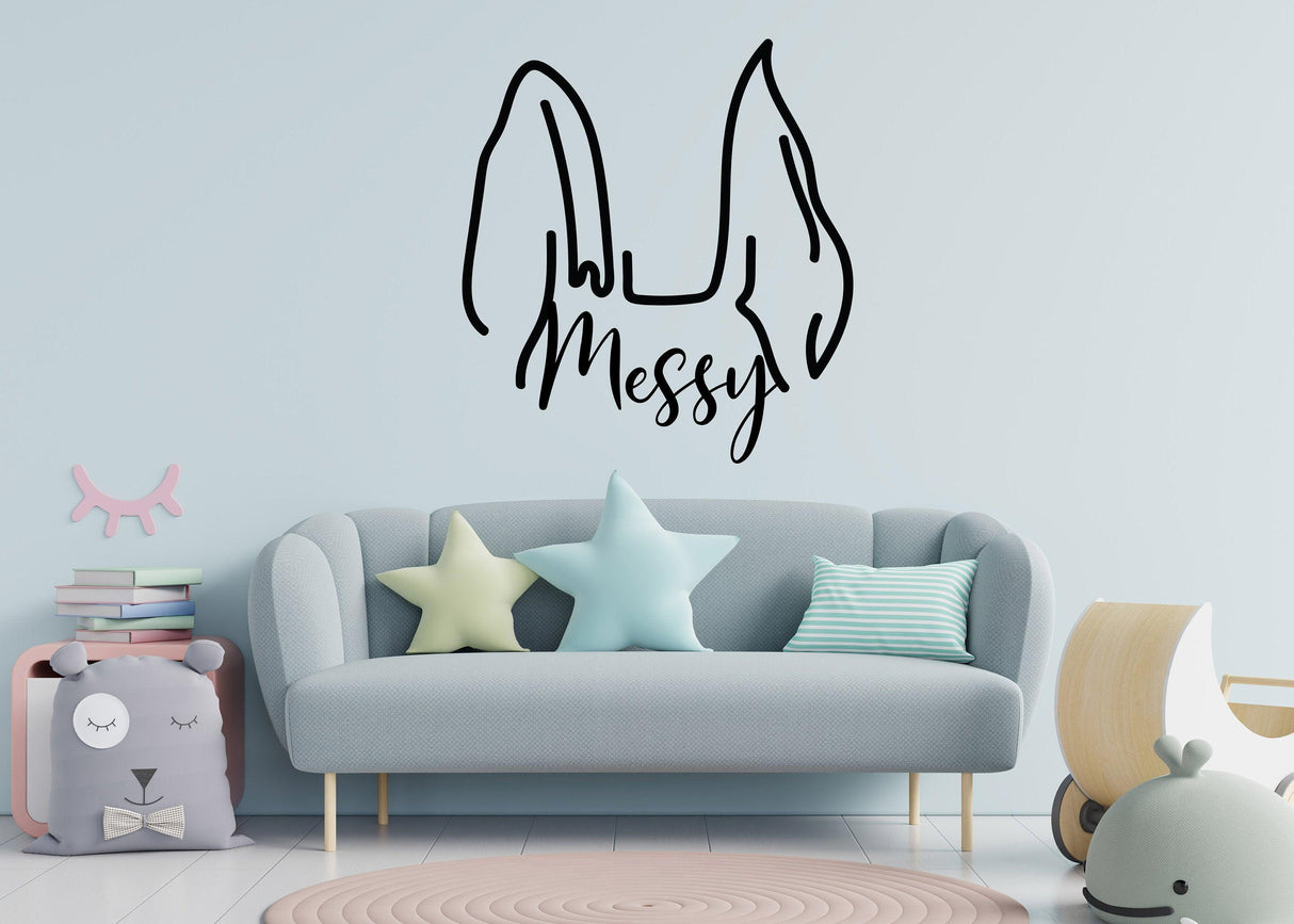 Customized pet ear decal 'Messy' on a wall above a stylish sofa in a modern living space.