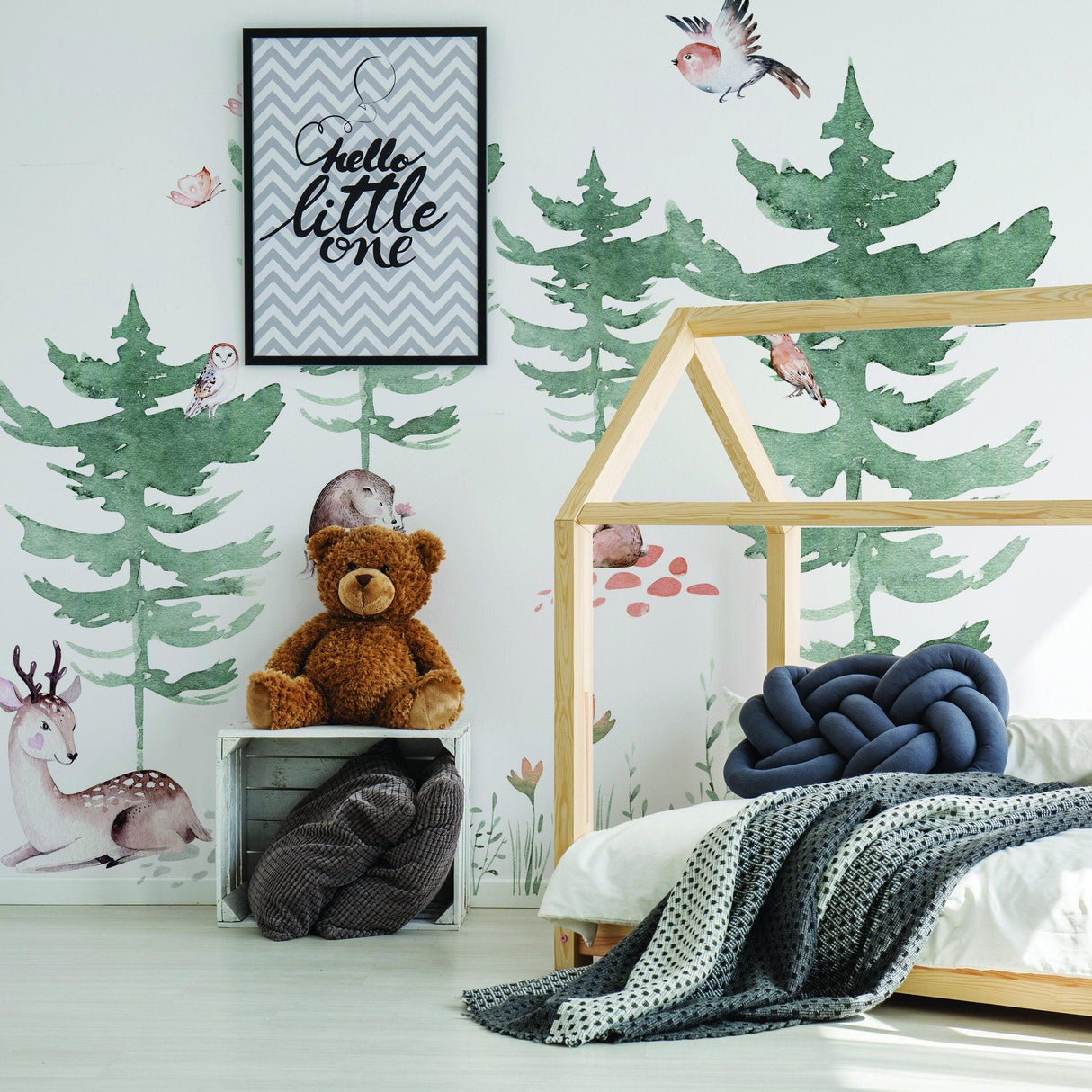 Whimsical woodland nursery featuring vinyl wall decals of trees, animals, and cozy decor for a playful child’s room.