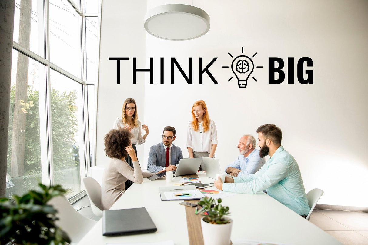 Group of professionals in a modern office with 'THINK BIG' motivational wall decal.