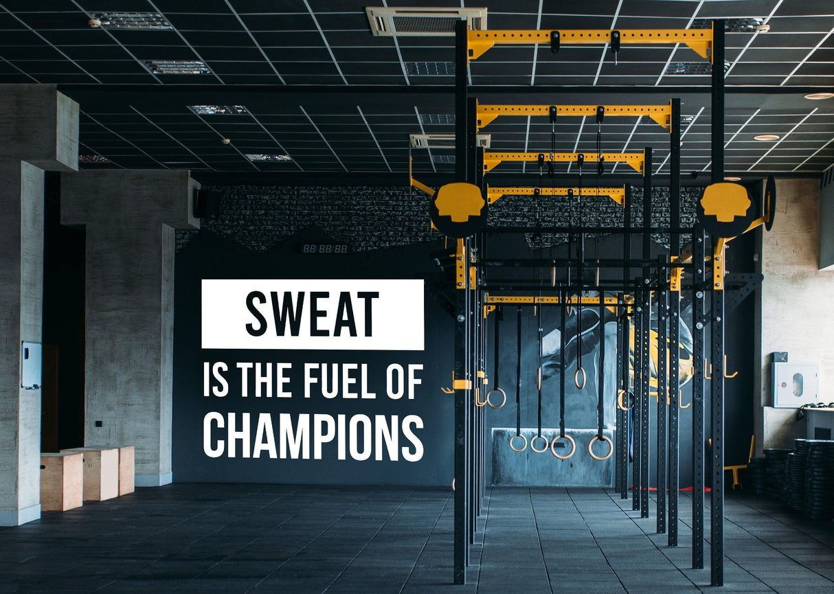 Gym interior with motivational quote 'Sweat is the Fuel of Champions' on the wall, inspiring fitness enthusiasts.
