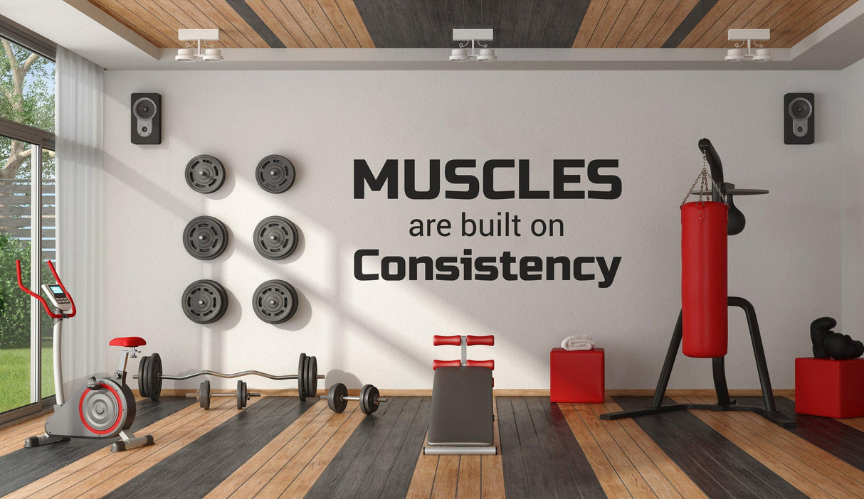 Motivational gym wall decal showcasing 'Muscles are built on Consistency' in a modern fitness space.