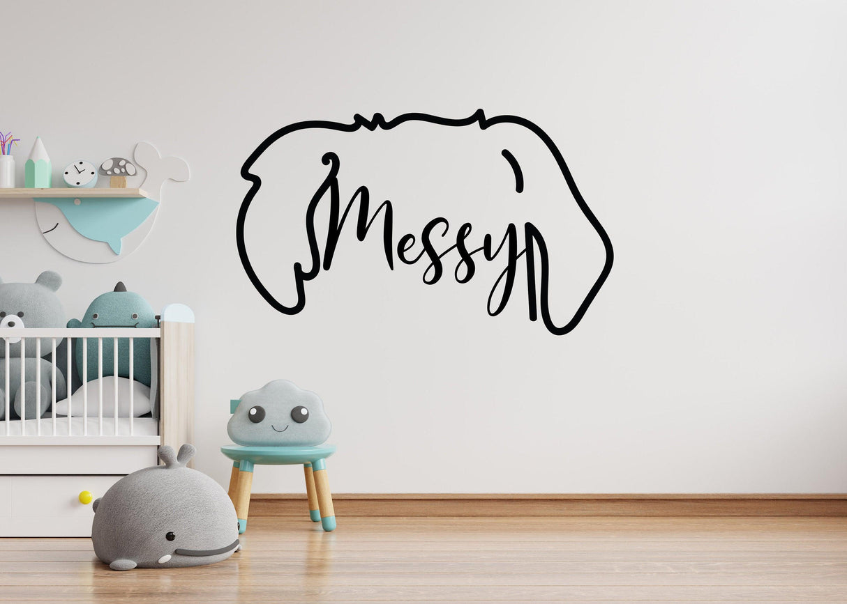 Custom dog ears outline decal with the word 'Messy' in a playful font on a nursery wall.