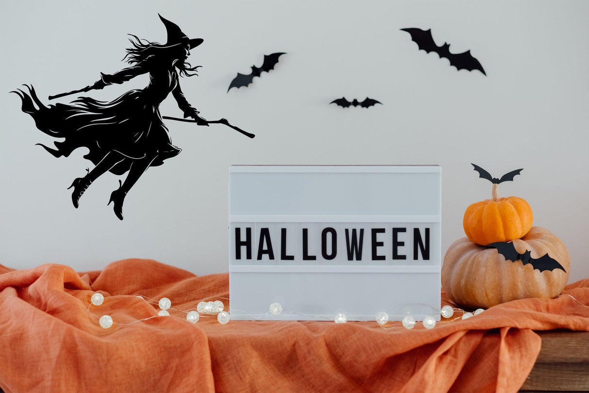 Flying witch broom silhouette decal for Halloween window art with pumpkins and bats.