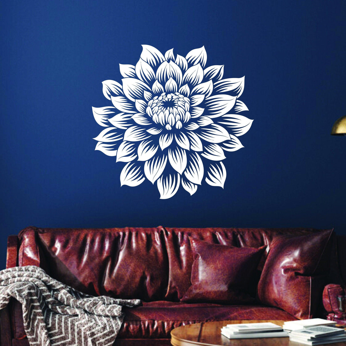 Oversized white vinyl flower wall decal on navy wall above a cozy brown leather sofa, enhancing home decor.