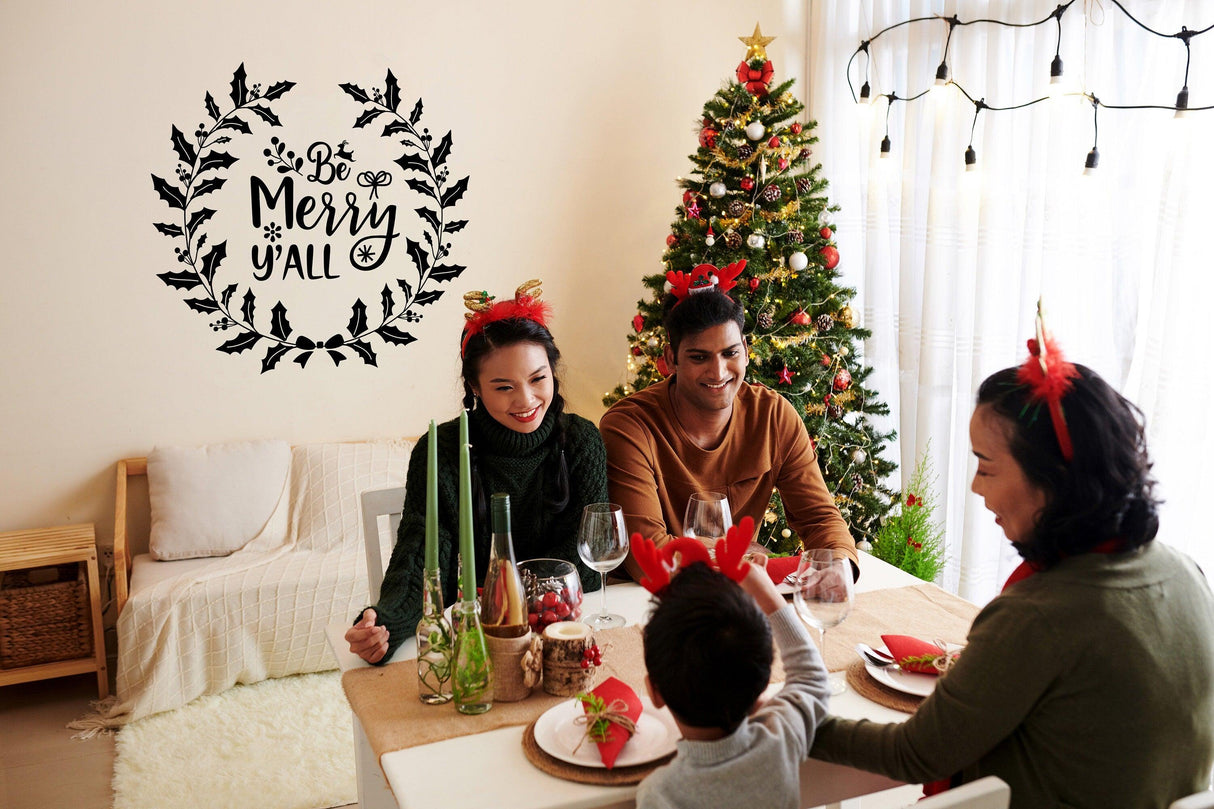 Family gathering around a festive table with the 'Be Merry y'all' Christmas vinyl sticker on the wall.