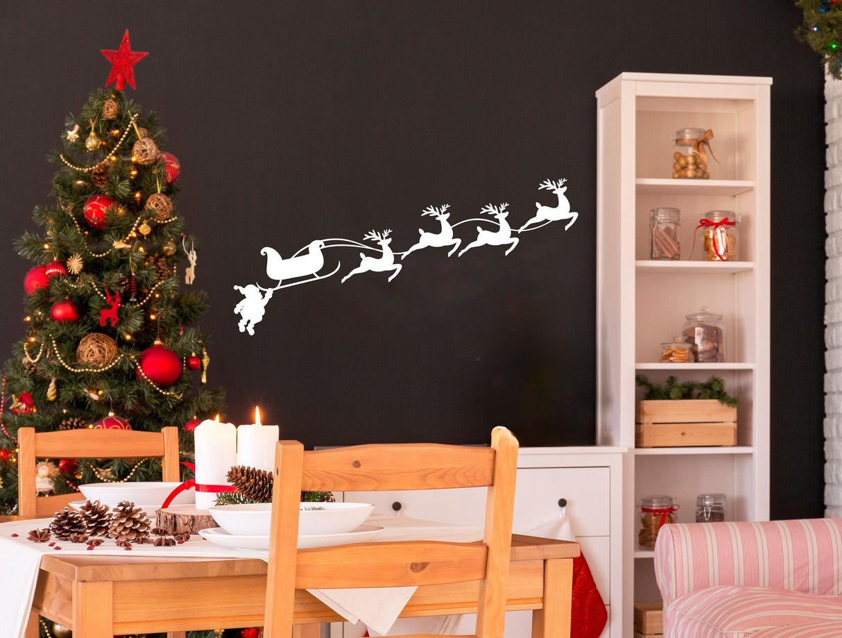 Humorous Santa in sleigh with reindeer wall decal above a festive dining area with Christmas tree.