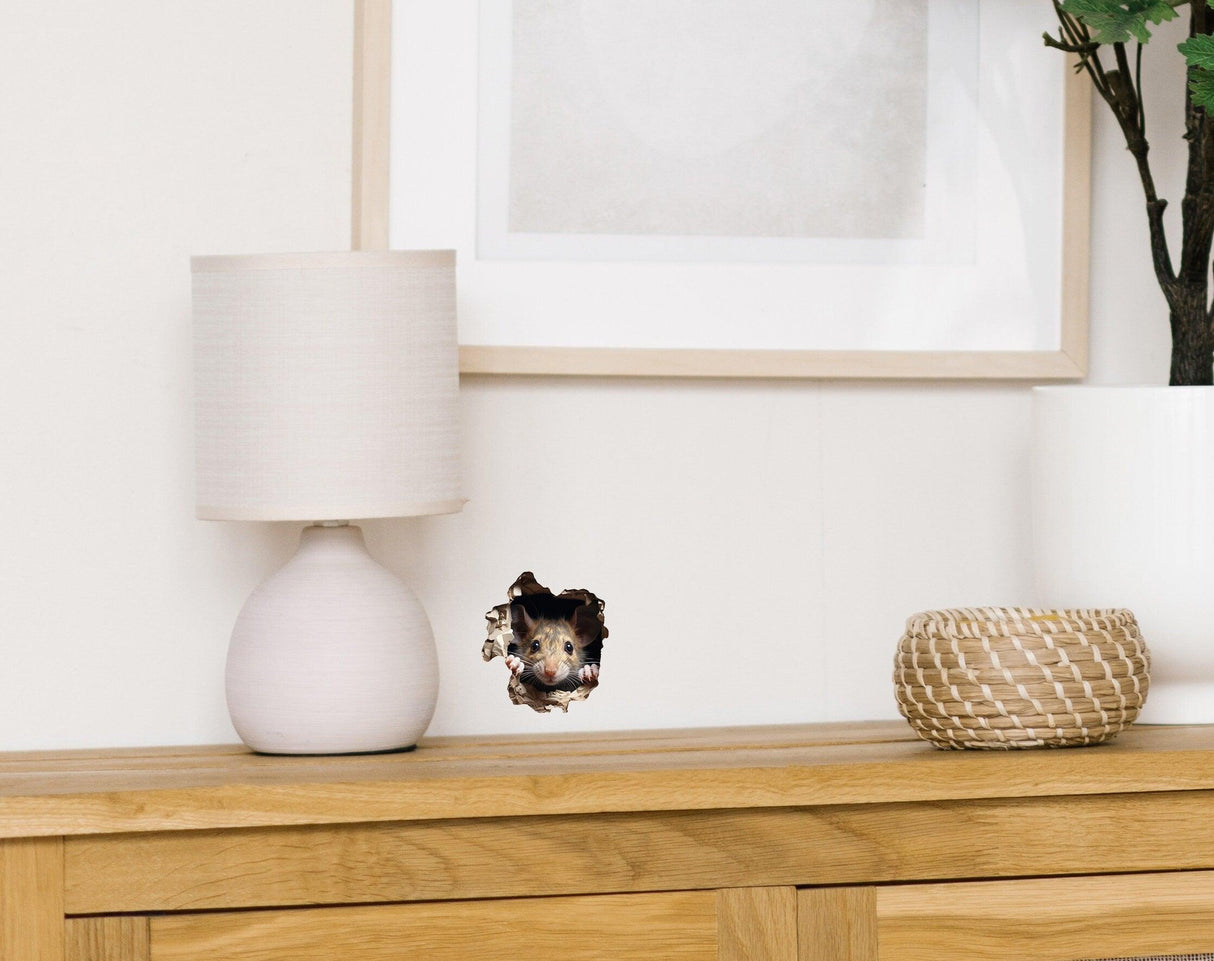 Lifelike 3D mouse wall sticker peeking out of a mousehole next to a lamp and decor on a wooden surface.