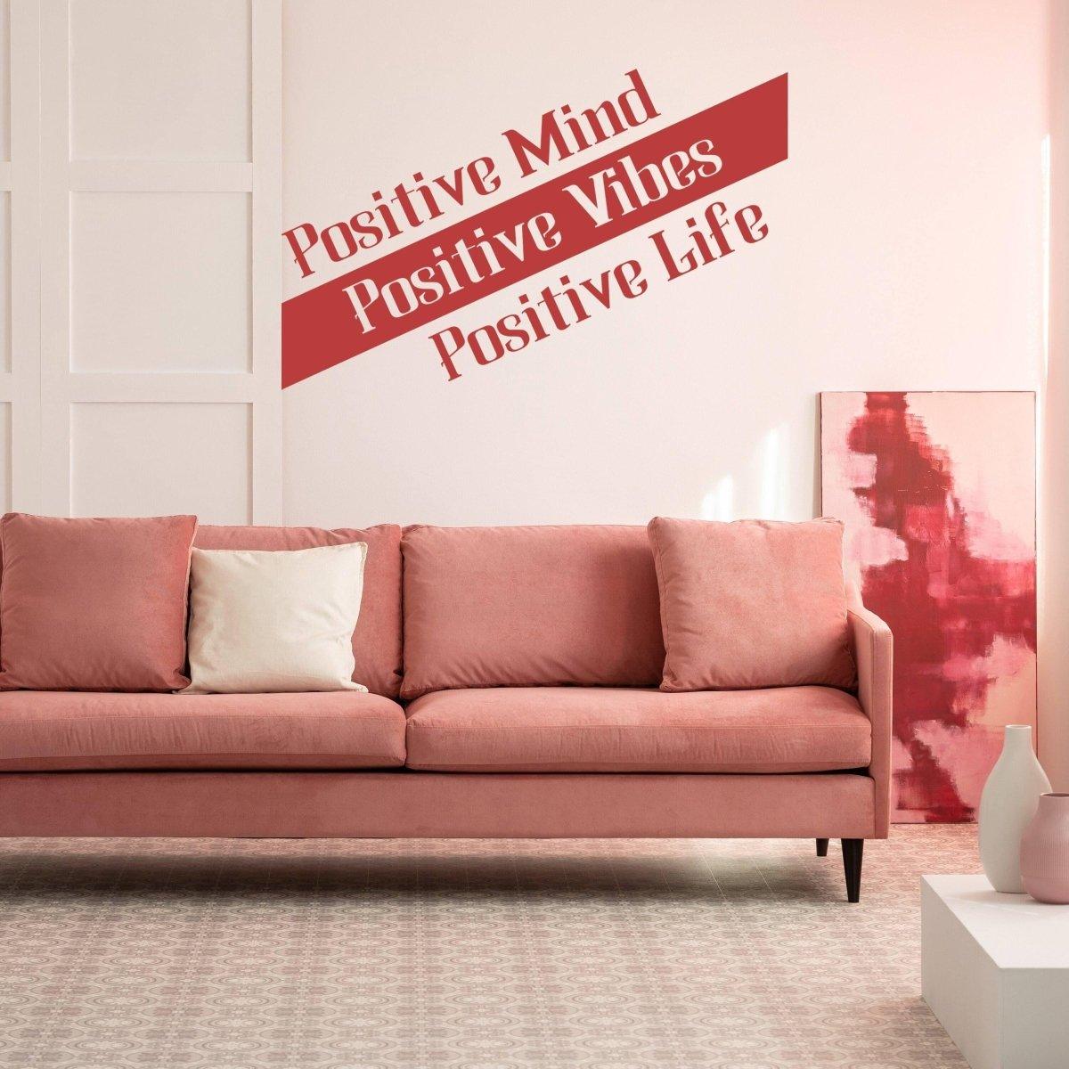 Living room with a pink sofa and inspirational wall decal saying 'Positive Mind, Positive Vibes, Positive Life'.
