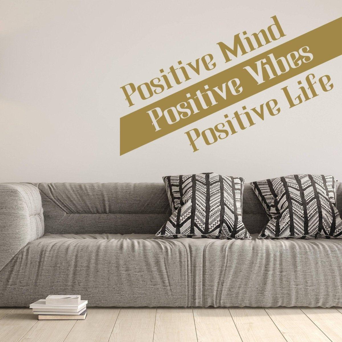 Inspirational wall decal reading 'Positive Mind, Positive Vibes, Positive Life' above a gray sofa with patterned pillows.