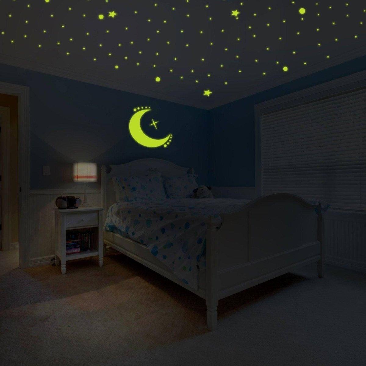 Custom glow-in-the-dark wall decals featuring stars and a moon design illuminating a bedroom at night.