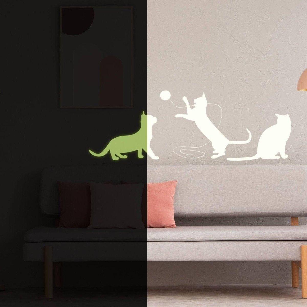 Glow in the dark cat wall decal on a beige wall above a couch with pillows.