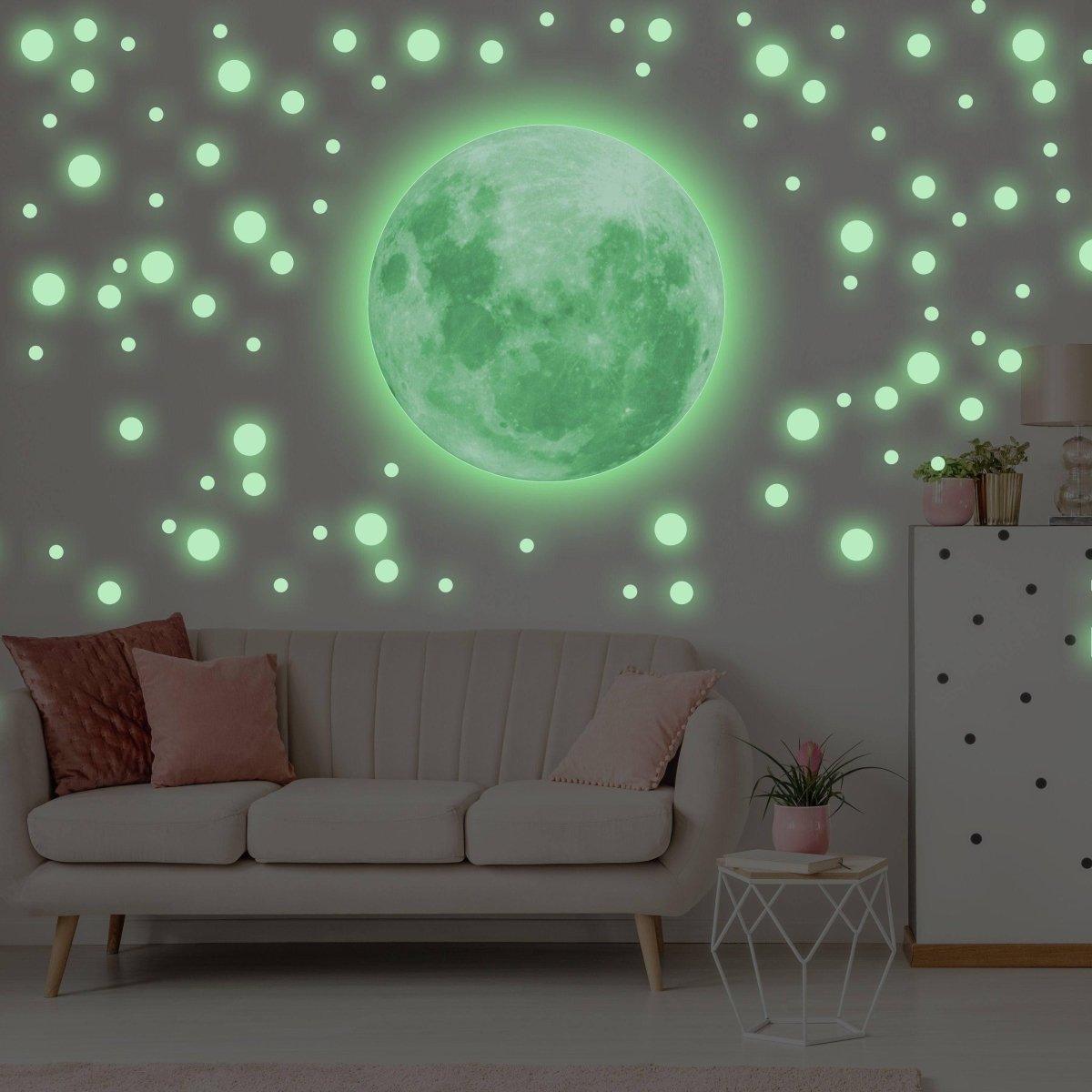 Glowing celestial night sky wall decal featuring a luminous moon and stars in a cozy living room setting.