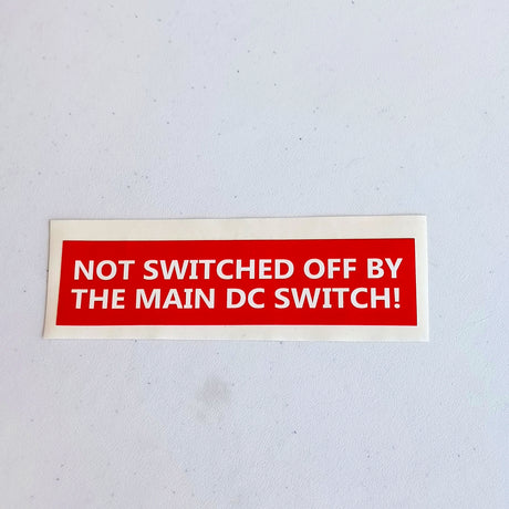 Red and white main DC switch electrical warning label shown as a product close-up.