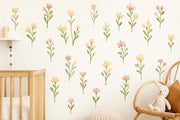 A nursery wall decorated with soft pastel flower decals in peach, blush, and yellow tones.