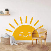 Smiling sun wall decal in a nursery, bright yellow with cheerful facial features.