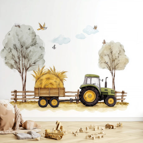 A farm-themed nursery wall decal showing a green tractor pulling a hay-loaded wooden trailer along a dirt path, with trees, birds, clouds, and a wooden fence in a soft watercolor style above a scattered toy scene on a wood floor.