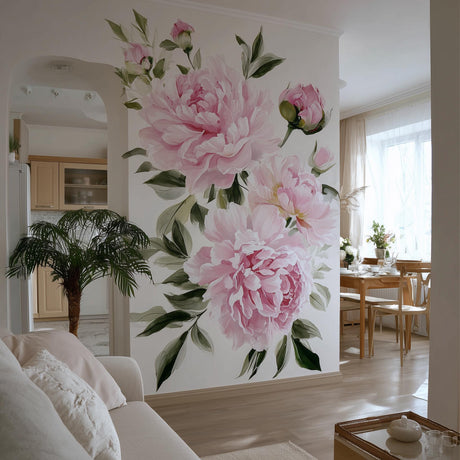 A bright, elegant living space with a large wall mural featuring soft pink watercolor peonies and green leaves. The floral design fills an accent wall between a cozy sitting area and a natural wood dining space, adding romantic charm and vibrancy.