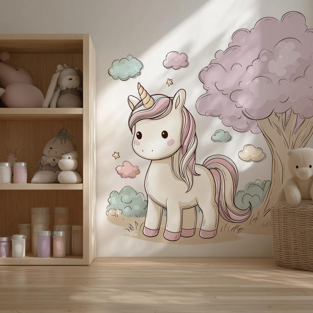 A cozy children’s room with a large wall decal of a pastel cartoon unicorn beside a fluffy pink tree and surrounded by soft clouds and stars. The design features a sweet and whimsical aesthetic in shades of cream, pink, and mint, perfect for a girl’s nursery or bedroom.