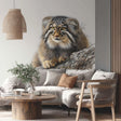 Realistic vinyl wall decal of a Pallas’s cat (manul) resting on a rock, with lifelike textures and colors. The decal is cut to shape and applied to a smooth wall above a beige sofa in a cozy, nature-inspired living room.