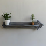 3D printed minimalist arrow-shaped wall shelf with modern geometric design, matte PLA texture, decorated with small plants