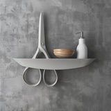 3D printed wall shelf shaped like a pair of scissors, mounted on wall, modern minimalist and creative home decor accessory
