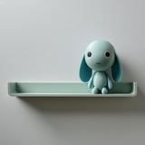3D printed wall shelf with an integrated bunny character and a small plant pot beside it, made of matte PLA plastic and mounted on a light wall.