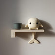 3D printed wall shelf with a small whale character on the ledge and a tail fin support beneath, made of matte PLA plastic on a light-colored wall.