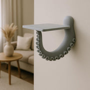 A sculptural 3D printed wall shelf designed to resemble a curled octopus tentacle with suction cups.