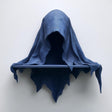 3D printed matte PLA wall shelf shaped like a hooded cloaked wraith with a small straight ledge, mounted on a light-colored wall.