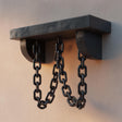3D printed gothic wall shelf with decorative black chains hanging from the underside, mounted on a light-colored wall.