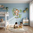 A cheerful cartoon monkey with brown fur and rosy cheeks smiling while hanging from a leafy green vine, designed as a vinyl wall decal for a children's room.