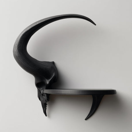 3D printed matte PLA wall shelf with a stylized ram skull and long curved horn supporting a small floating ledge on a light-colored wall.