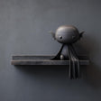 3D printed matte PLA wall shelf with a small vampire bat character and cape sitting on a double-step ledge against a dark wall.
