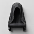 3D printed matte black wall shelf shaped like a hooded cloaked figure with a dark empty face and a small ledge at the bottom, mounted on a light wall.