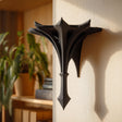 Small gothic-style 3D printed wall shelf bracket with a pointed spire shape, mounted on a light wall and used as a decorative display ledge.