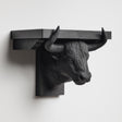 3D printed bull head wall shelf with long curved horns supporting a flat floating ledge, mounted on a clean minimalist wall.