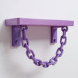 3D printed pastel purple wall shelf with two brackets and a decorative hanging chain, mounted on a clean white wall.