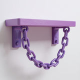 3D printed pastel purple wall shelf with two brackets and a decorative hanging chain, mounted on a clean white wall.